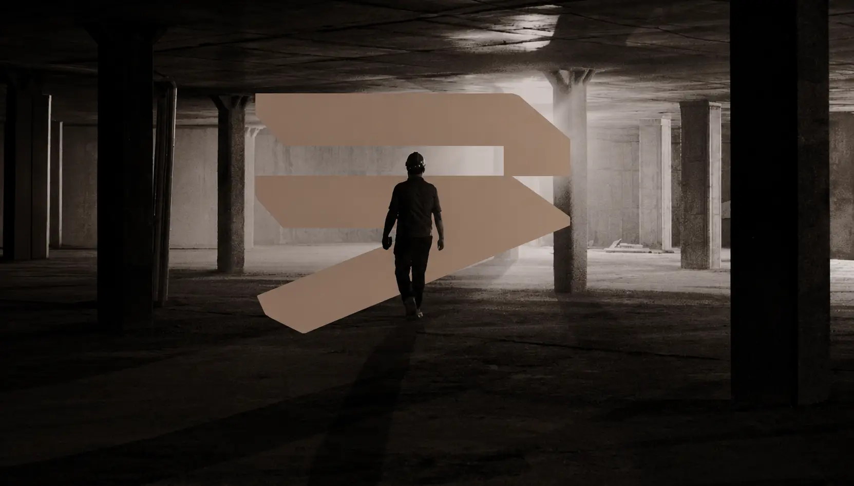 Construction worker walking through unfinished building with Ground UP Construction brand mark, Dubai